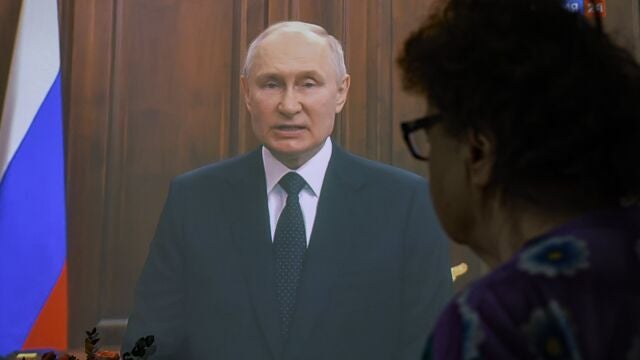 una mujer escucha el discurso a la nación de Vladimir Putin del pasado sábado