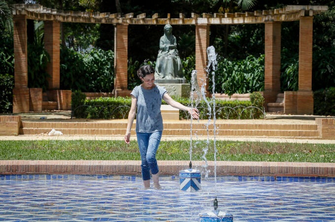 Una mujer se refresca en una fuente en plena ola de calor en Sevilla 