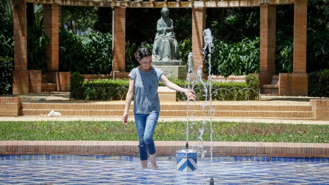 Una mujer se refresca en una fuente en plena ola de calor en Sevilla 