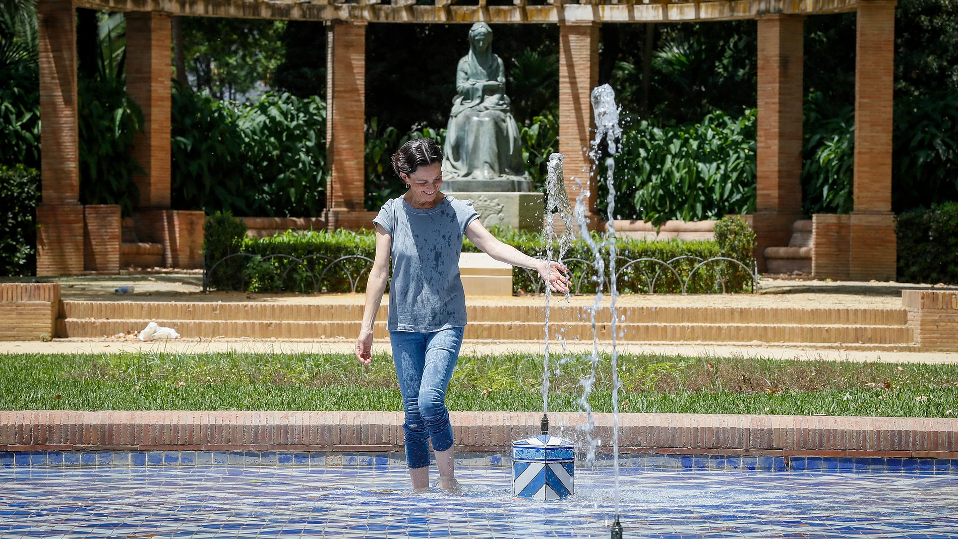 Una mujer se refresca en una fuente en plena ola de calor en Sevilla