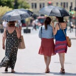  Tres mujeres se protegen del calor con unos paraguas en Valencia