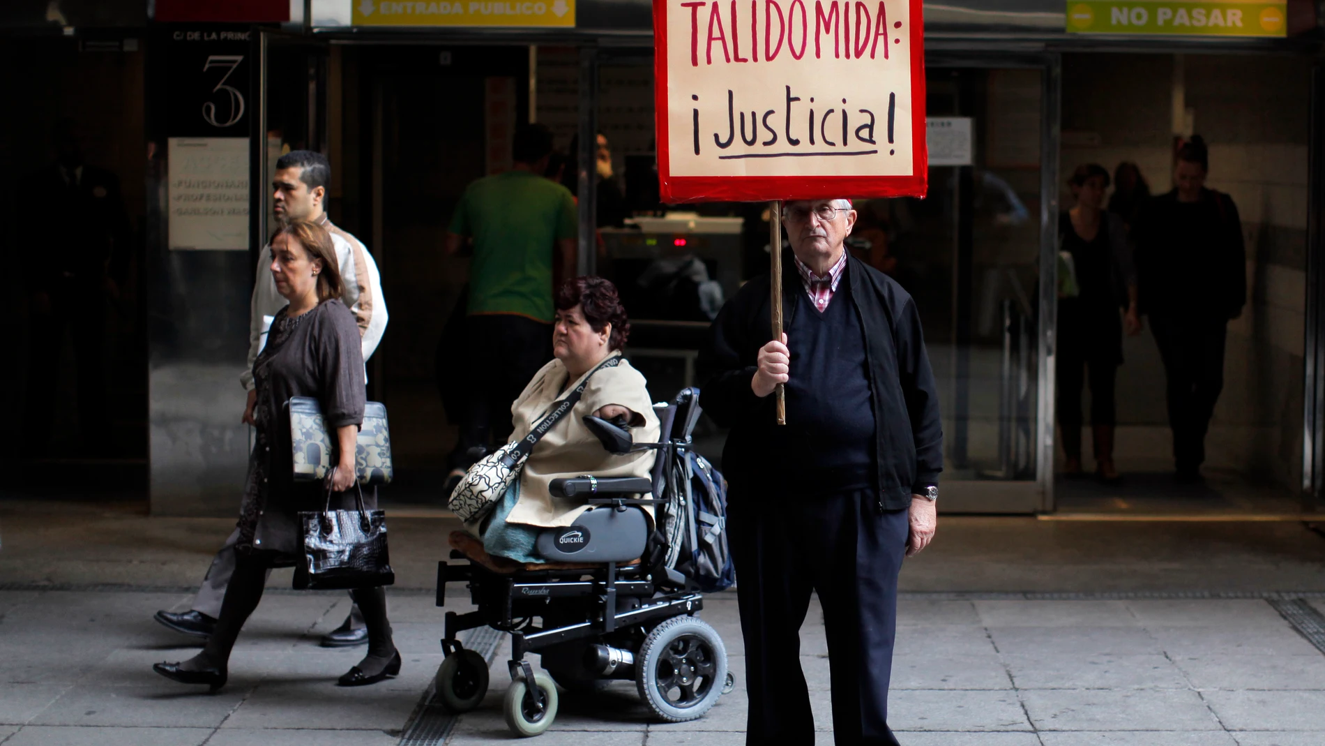 Una víctima de la talidomida muestra un cartel reclamando justicia