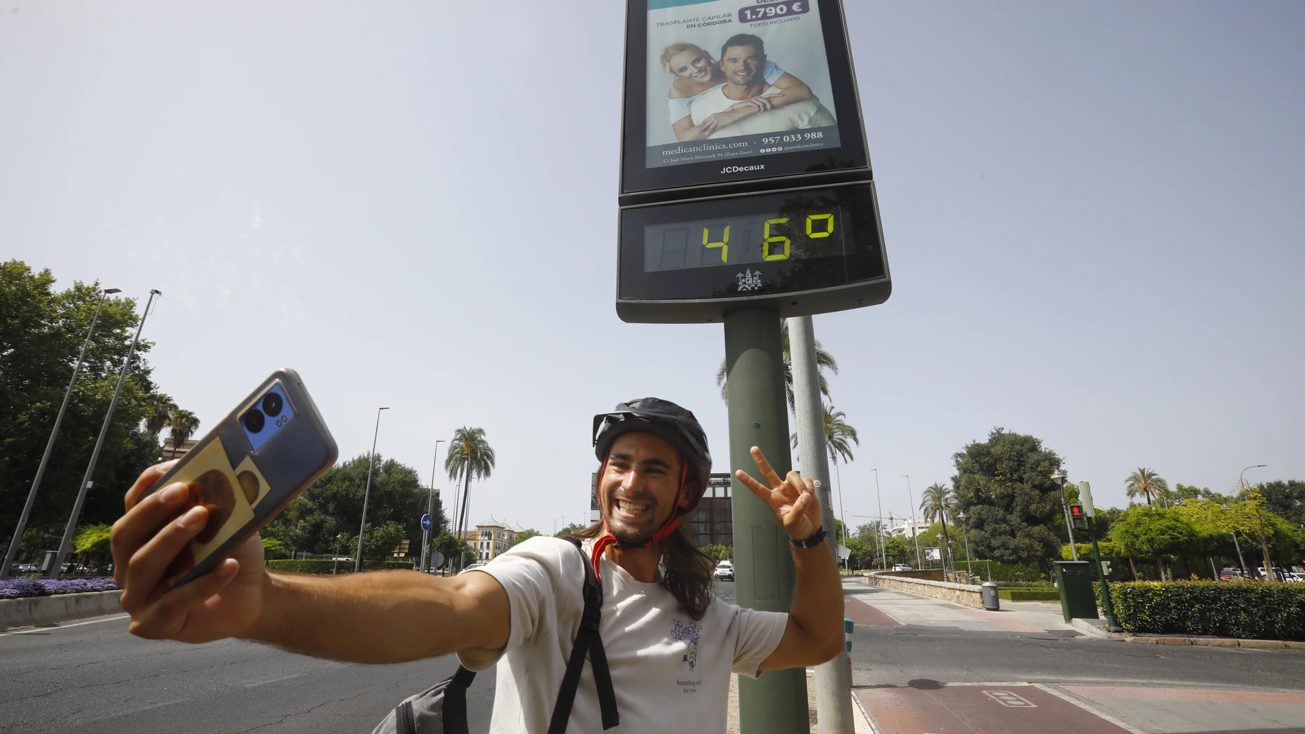 . CÓRDOBA, 11/07/2023.- Un joven se fotografía delante de un termómetro de calle en Córdoba que marca 46 grados, este martes cuando la Agencia Estatal de Meteorología (AEMET) alerta de temperaturas máximas en el interior de Andalucía con una previsión de 43 grados en las ciudades de Córdoba y Granada y de 42 en Jaén y Sevilla. EFE/Salas