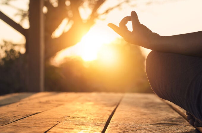Mujer practicando yoga y meditación en posición de loto en la puesta de sol.