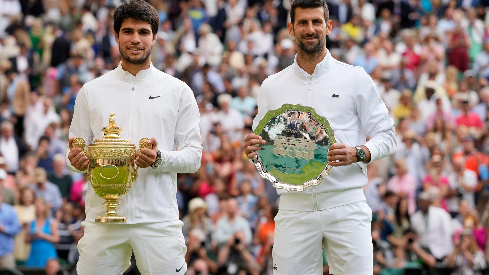 Spain's Carlos Alcaraz, left, celebrates with the trophy after beating Serbia's Novak Djokovic, right, to win the final of the men's singles on day fourteen of the Wimbledon tennis championships in London, Sunday, July 16, 2023. (AP Photo/Kirsty Wigglesworth)