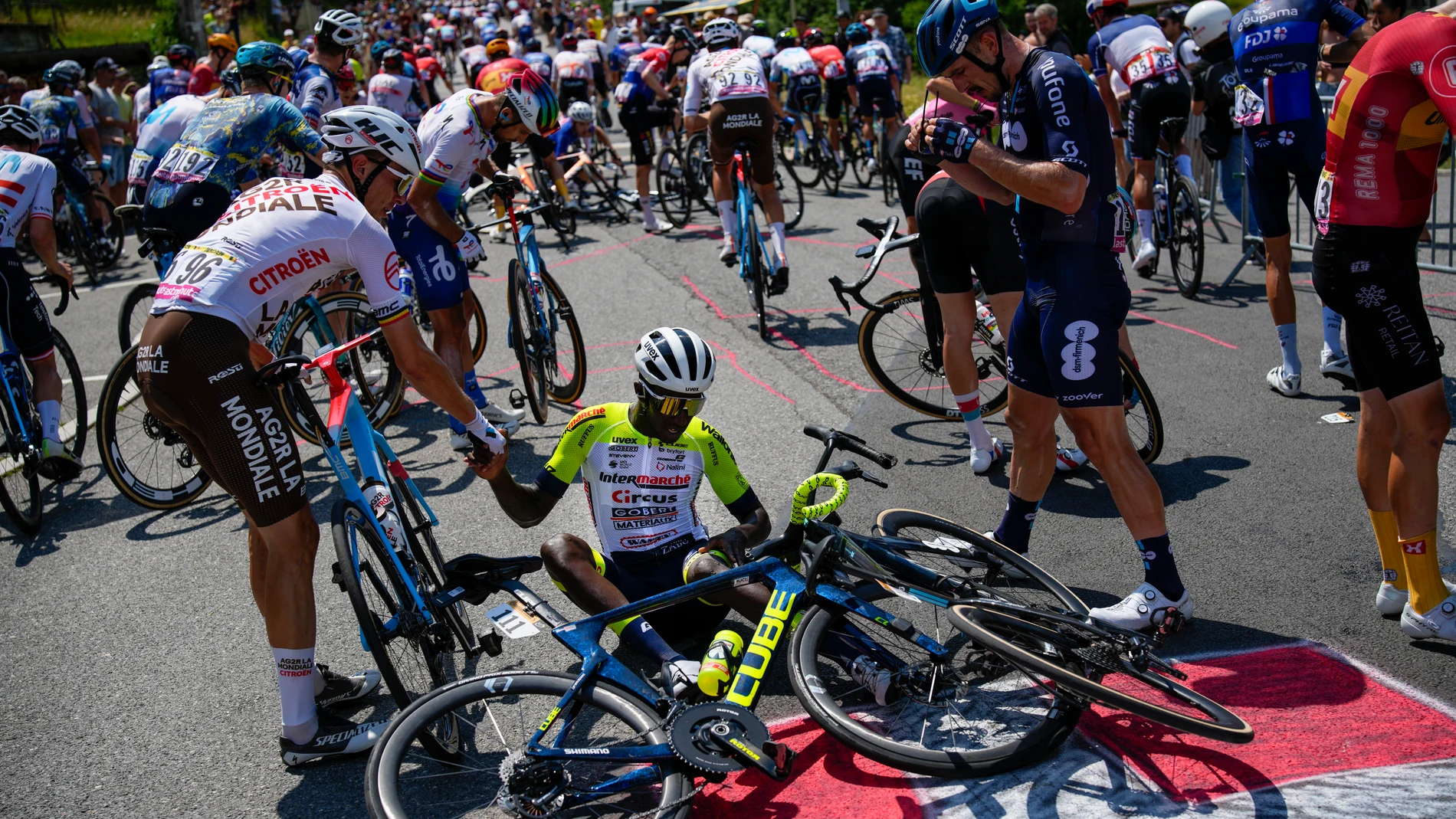 Eritrea's Biniam Girmay gets a helping hand from Belgium's Olivier Naesen, left, after crashing during the fifteenth stage of the Tour de France cycling race over 179 kilometers (111 miles) with start in Les Gets Les Portes du Soleil and finish in Saint-Gervais Mont-Blanc, France, Sunday, July 16, 2023. (AP Photo/Daniel Cole)