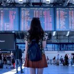 Mujer mirando la pantalla con las salidas de un aeropuerto 