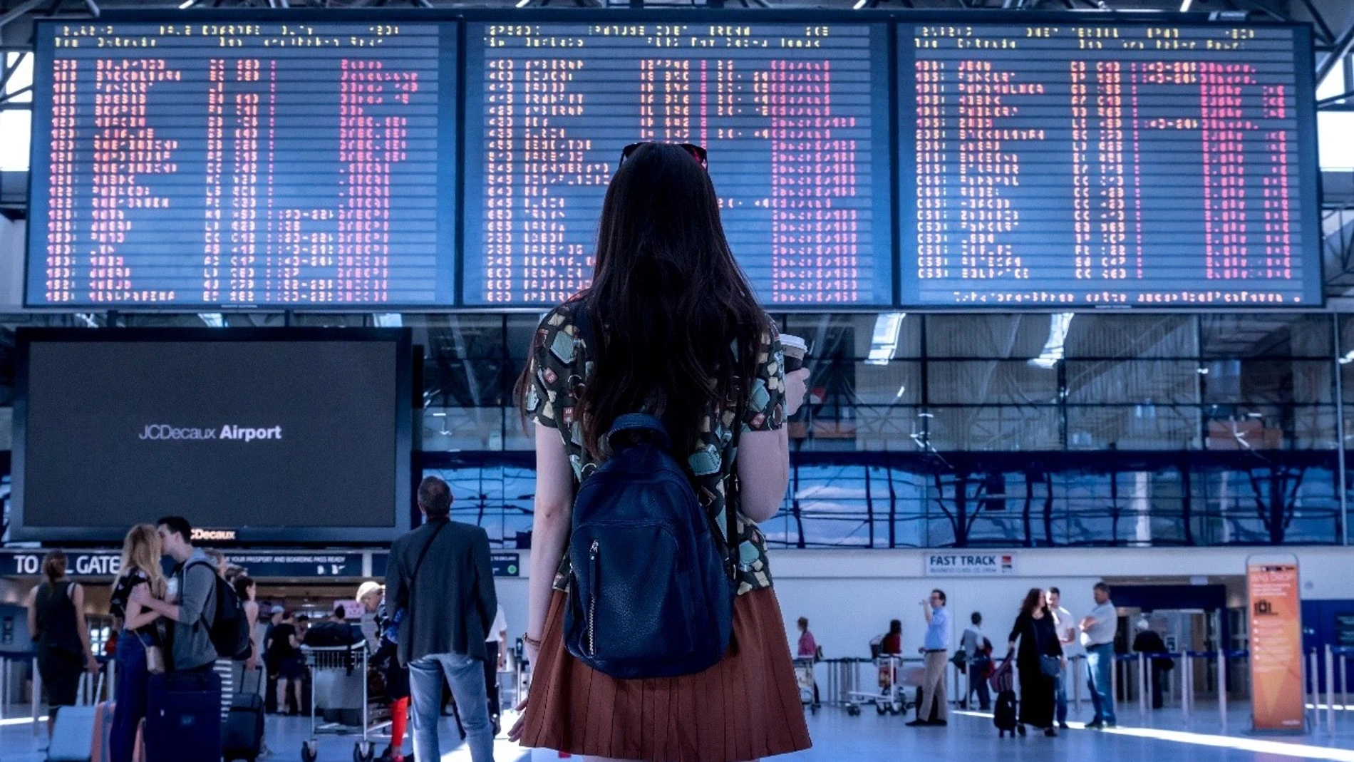 Mujer mirando la pantalla con las salidas de un aeropuerto 