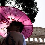 Una turista se protege del sol mientras visita los alrededores del Coliseo en Roma