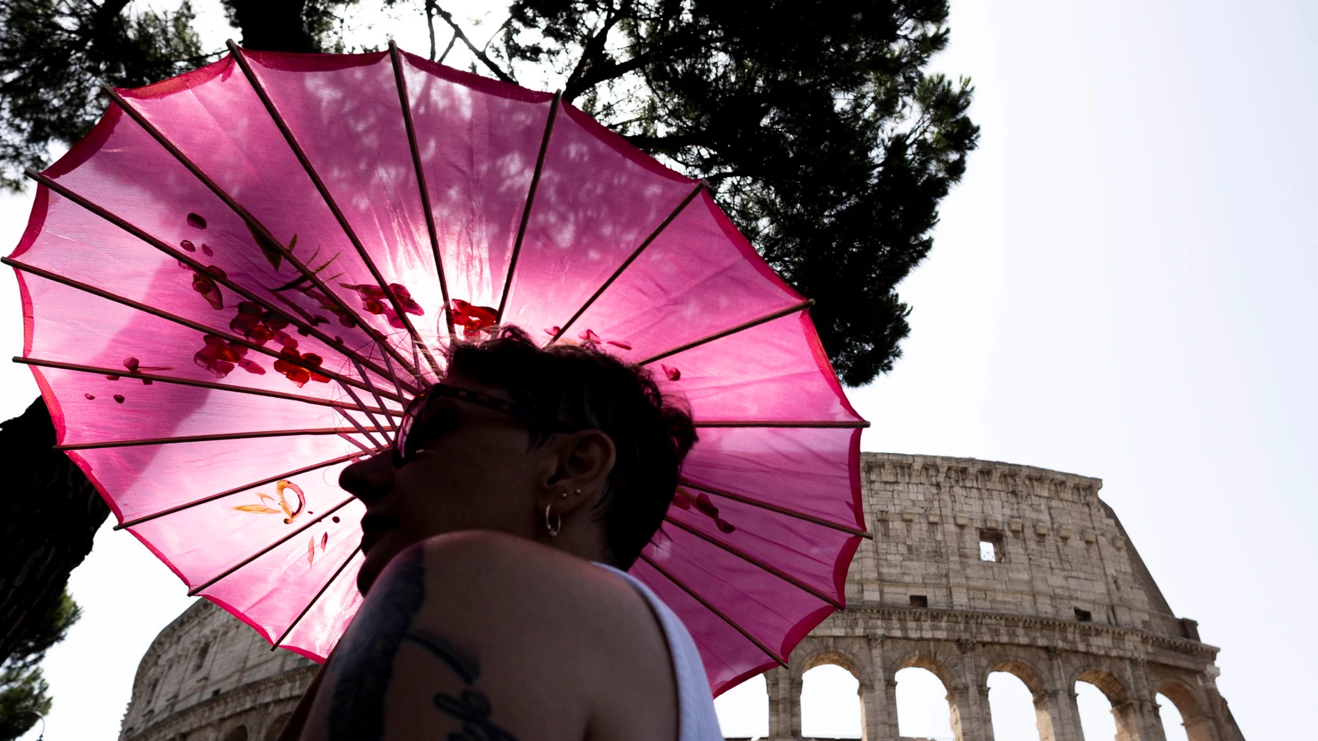 Una turista se protege del sol mientras visita los alrededores del Coliseo en Roma