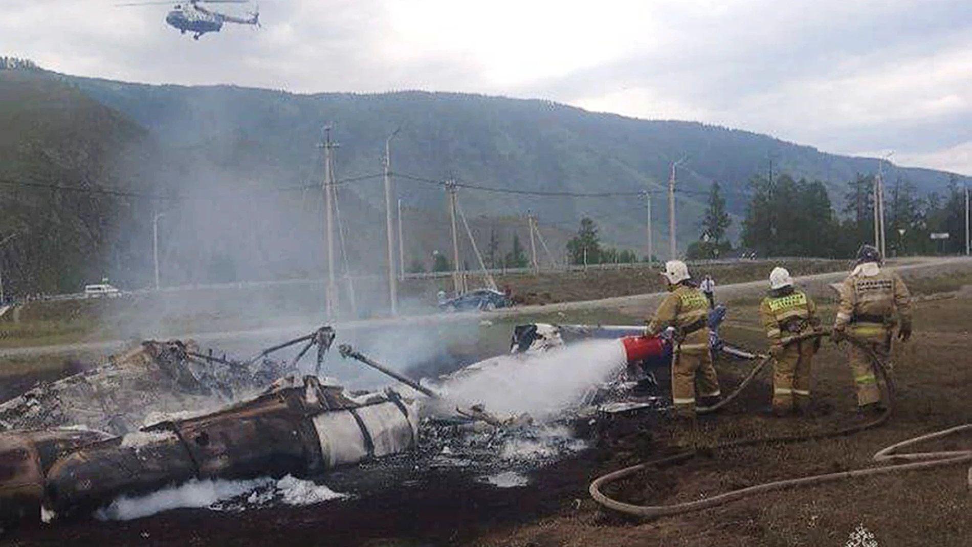 In this image provided by Russian Emergency Situations Ministry press service, firefighters extinguish a Mi-8 helicopter after the crash near Tyungur village, Altai Republic in southern Siberia, Russia, Thursday, July 27, 2023. A helicopter crashed in Russia's Siberia on Thursday, killing six of those on board and injuring seven, Russian emergency officials reported. (Ministry of Emergency Situations press service via AP)