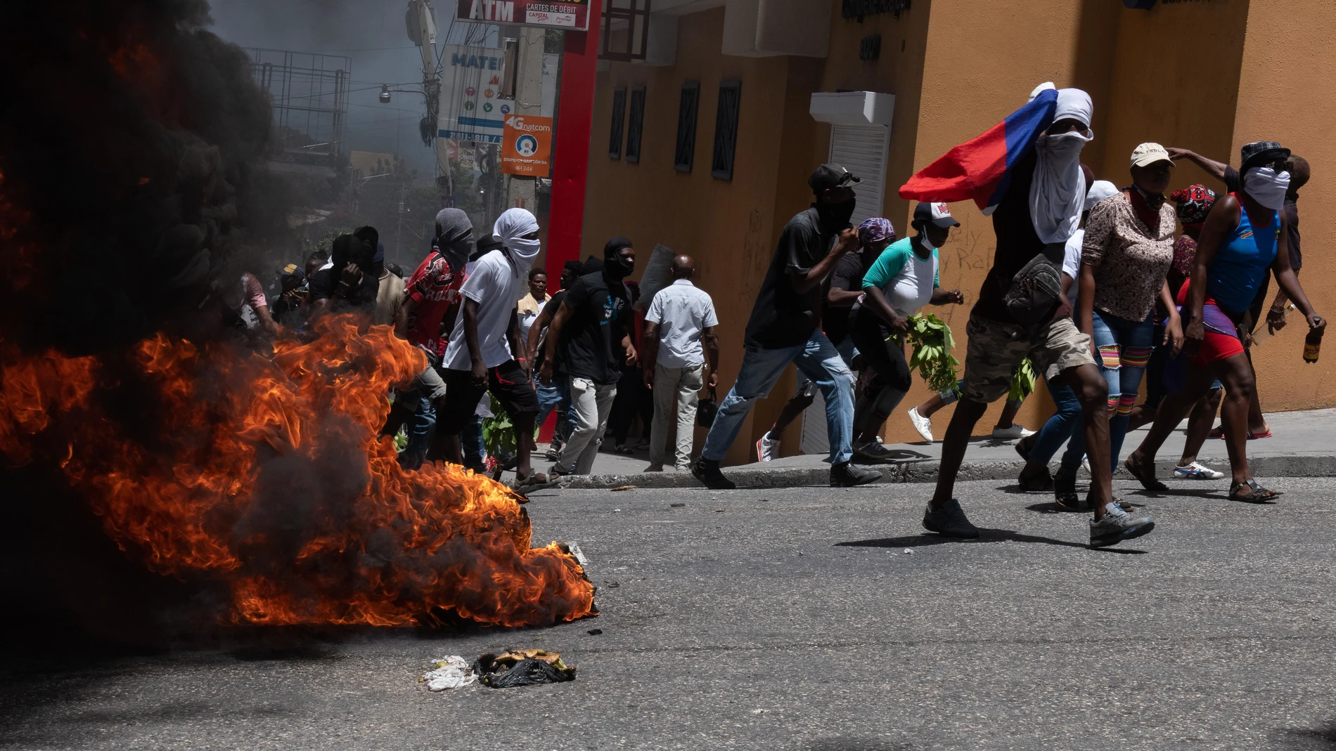 AME8814. PUERTO PRÍNCIPE (HAITÍ), 07/08/2023.- Manifestantes pasan junto a una barricada en llamas durante una marcha para exigir seguridad contra las pandillas hoy, en Puerto Príncipe (Haití). Cientos de haitianos salieron este lunes a las calles de Puerto Príncipe para manifestarse contra la situación de inseguridad, creada por la acción de las bandas armadas que obliga a miles de personas a convertirse en refugiados internos, y para criticar a las autoridades por su inacción. A lo largo de...