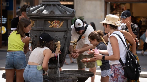 Varias personas se refrescan en una fuente de Barcelona durante una ola de calor