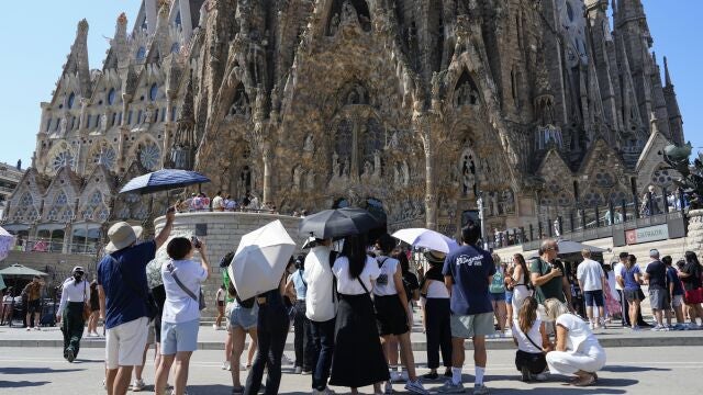 Varios turistas equipados con sombrillas visitan la Sagrada Familia, en Barcelona.