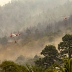 Dos helicópteros trabajan este viernes en las tareas de extinción del incendio en Candelaria (Santa Cruz de Tenerife) que ha arrasado 14.571 hectáreas, el mayor incendio forestal este año en España. Este enorme incendio ya tiene el perímetro consolidado con puntos calientes en la zona norte