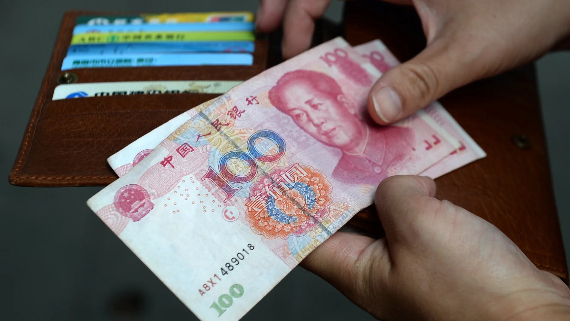A woman holds Chinese Yuan banknotes. 