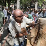 El escultor Alfredo Martín 'Chis' talla la cabeza de un león rodeado de visitantes de la exposción