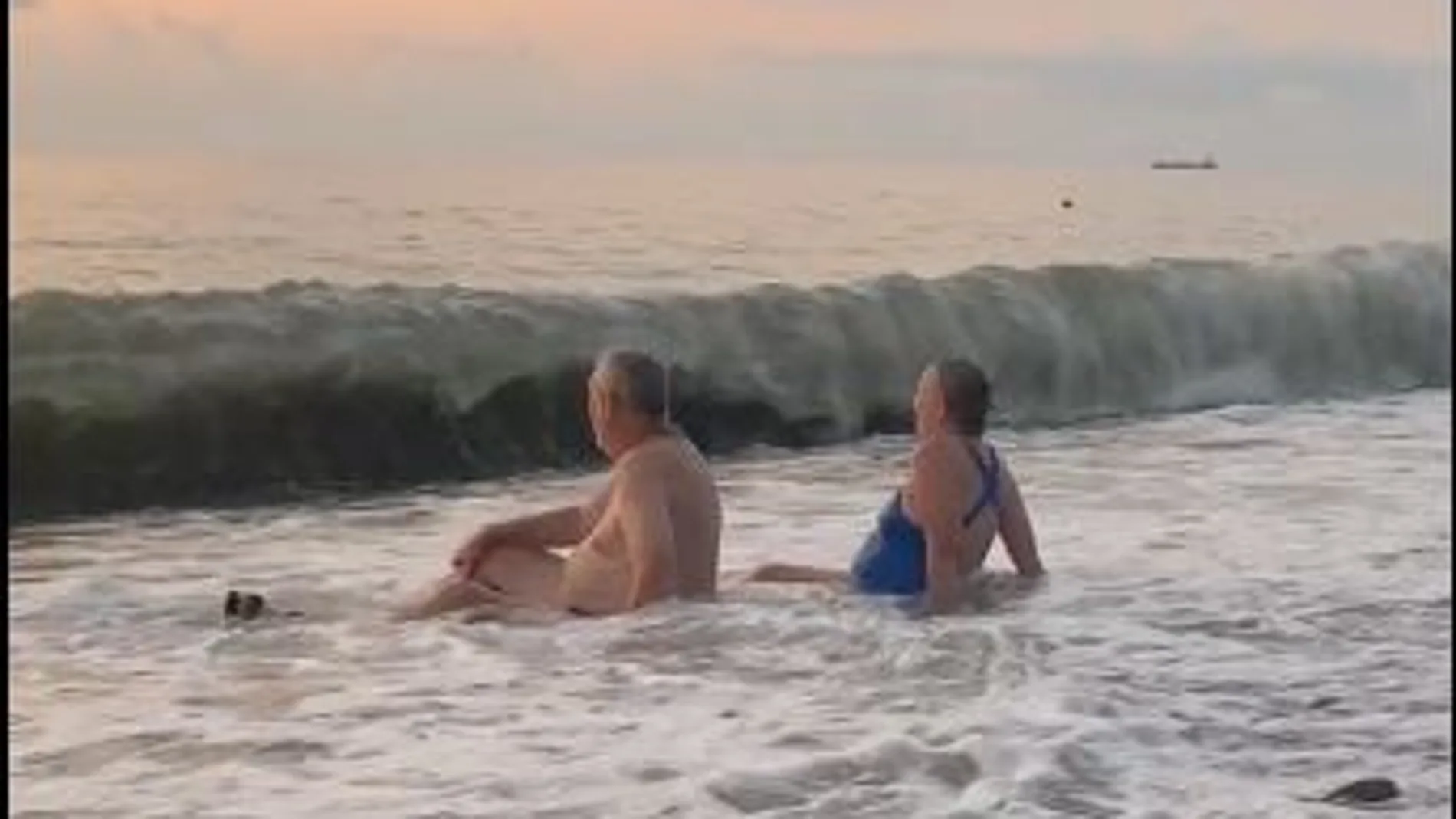 Pareja de abuelitos juegan con las olas del mar