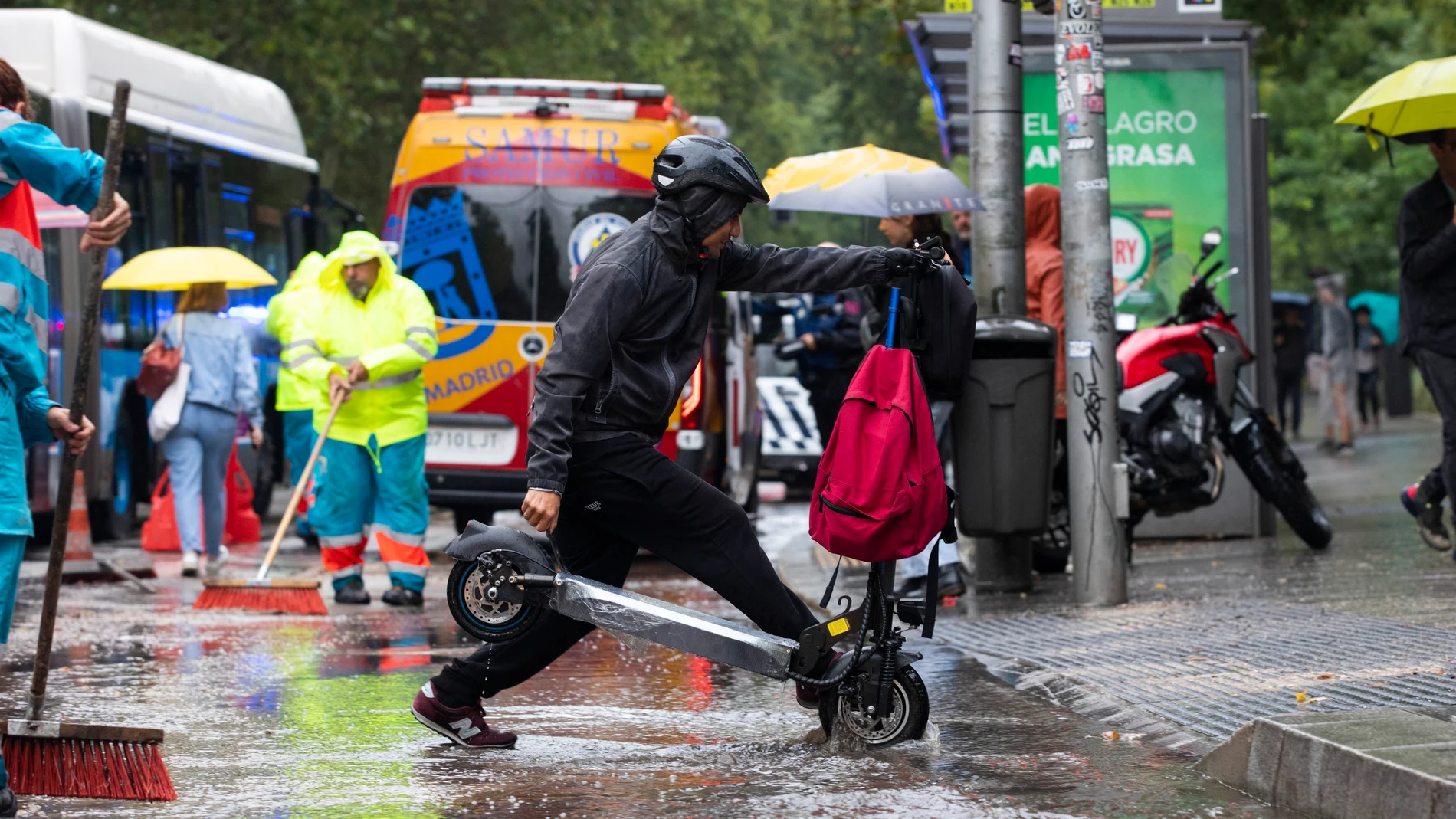Fuertes lluvias en Madrid por el paso de la Dana. Un joven cruza con su patinete eléctrico por un paso de peatones. © Jesús G. Feria.