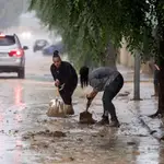 Varias personas retiran el lodo acumulado en Magán (Toledo) a causa de las fuertes lluvias caídas desde este sábado. 