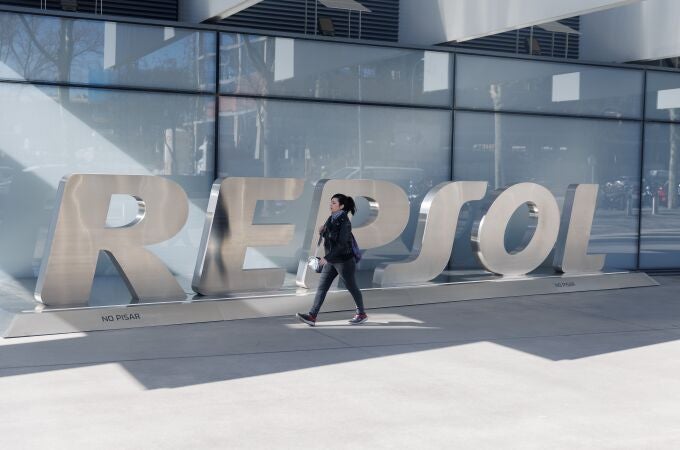 Una mujer camina frente a las letras Repsol en su sede, en Madrid (España). 