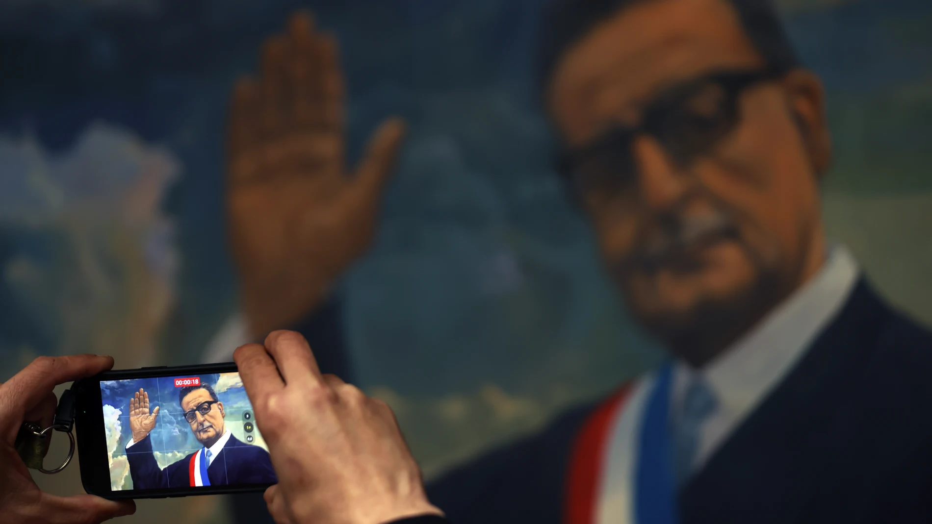 CH0. SANTIAGO (CHILE), 08/09/2023.- Una hombre toma una grabación sobre un cuadro de Salvador Allende, el 30 de agosto de 2023 en Santiago (Chile). La mayoría de los mandatarios de izquierda de la región asistirán el lunes a los actos conmemorativos por el 50° aniversario del golpe de Estado contra Salvador Allende, hoy referente para el progresismo mundial, pero incomprendido en la década de 1970, cuando en Latinoamérica se defendía principalmente la revolución socialista armada. EFE/ Elvis ...