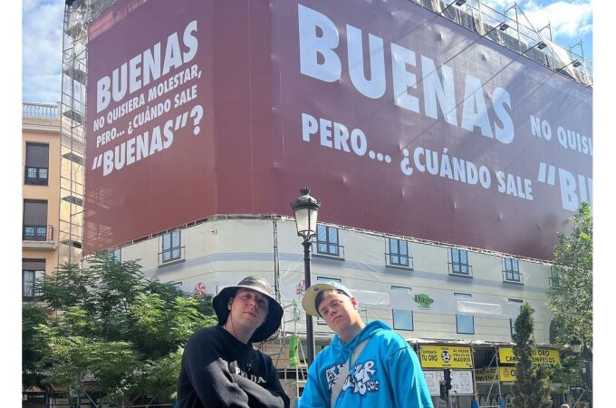 Quevedo y Saiko posan con el cartel promocional de su nueva canción 'Buenas'