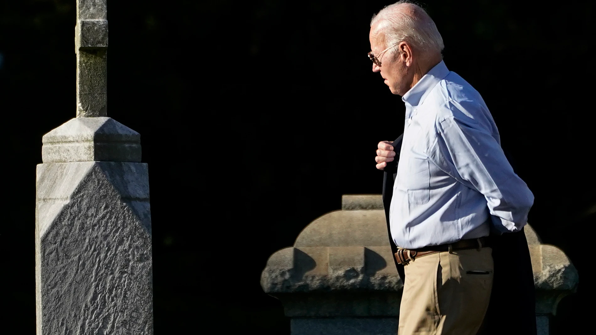 President Joe Biden puts his jacket on while walking between tombstones to attend Mass at St. Joseph on the Brandywine Catholic Church in Wilmington, Del., Saturday, Sept. 16, 2023. (AP Photo/Stephanie Scarbrough)