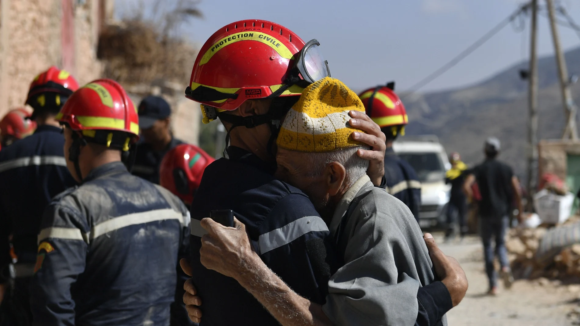 A man hugs a member of the civil protection team as they prepare to recover bodies of victims from a collapsed building, Imi Ntala, Amizmiz, south of Marrakesh, Morocco