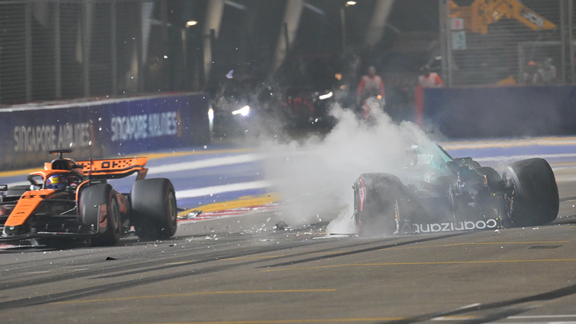 Smoke comes out of the car of Aston Martin driver Lance Stroll of Canada after a crash as Mclaren driver Oscar Piastri of Australia passes by during the qualifying session of the Singapore Formula One Grand Prix at the Marina Bay circuit, Singapore, Saturday, Sept. 16, 2023. (Caroline Chia/Pool Photo via AP)