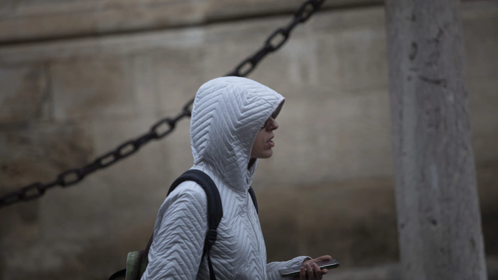 Una mujer se coloca la capucha para protegerse de la lluvia.