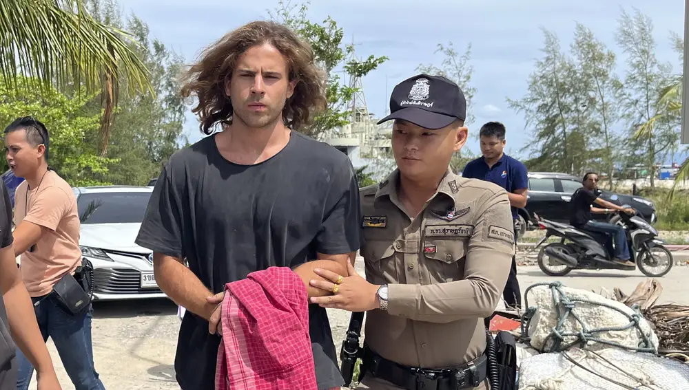 A Thai police officer escorts Spanish Daniel Sancho Bronchalo on suspicion of murdering and dismembering a Colombian surgeon from Koh Phagnan island to Koh Samui Island court, southern Thailand, Monday, Aug. 7, 2023. Sancho, the son of two Spanish film stars, has been arrested in Thailand on suspicion of murdering and dismembering Edwin Arrieta Arteaga on a tourist island, police said. Sancho was taken from Koh Phagnan, where the remains of the Colombian surgeon were found, to another island, Samui, where he is being held, Surat Thani provincial police commander Saranyu Chamnanrat said Tuesday. (AP Photo/Somkeat Ruksaman)