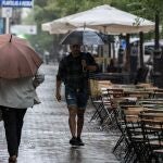 Varias personas se resguardan de la lluvia con paraguas