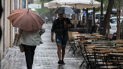 Varias personas se resguardan de la lluvia con paraguas