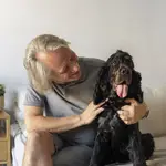 Una persona mayor sonríe a un perro