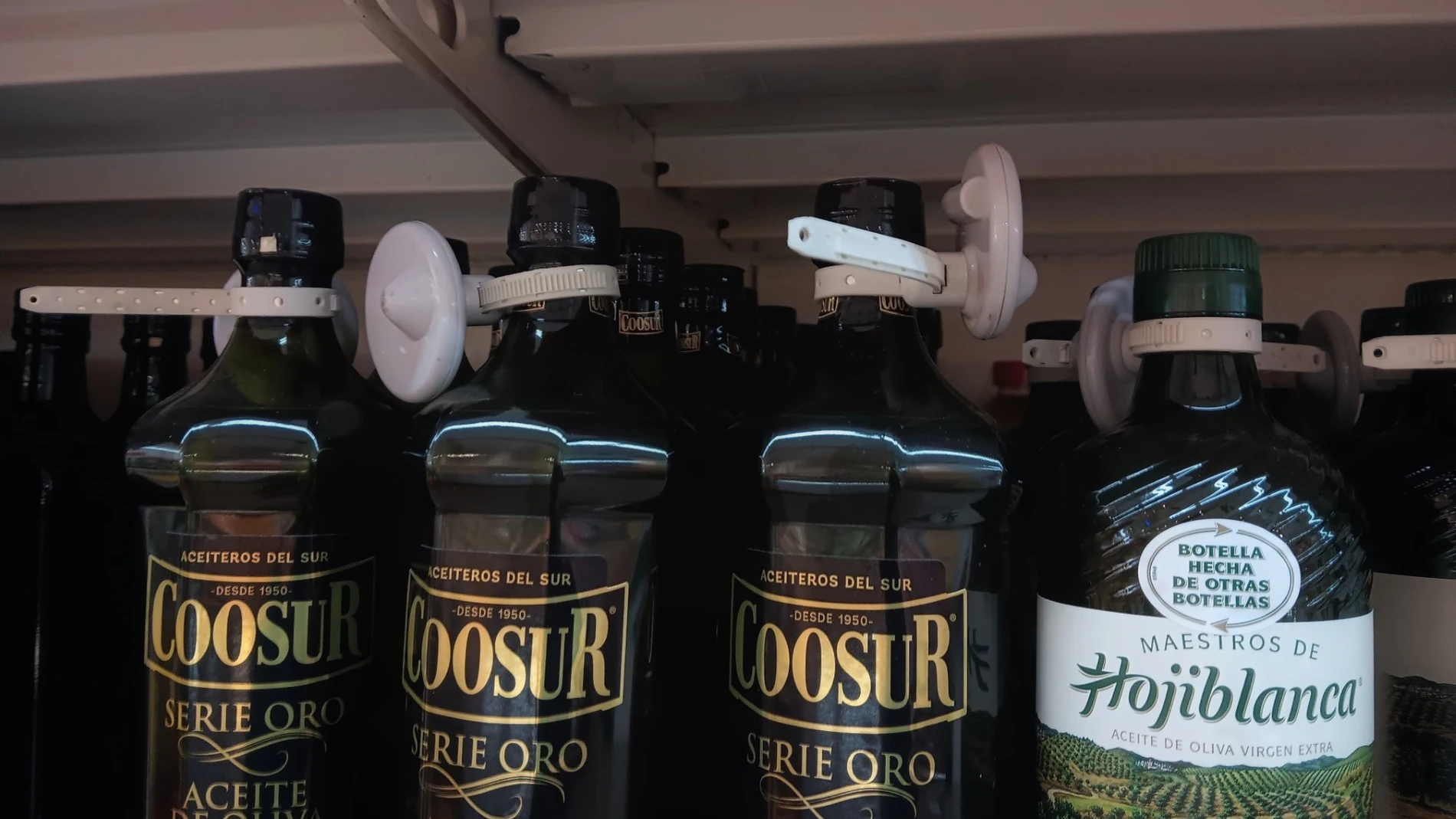 Envases de aceite de oliva virgen extra en un lineal de supermercado con un dispositivo de seguridad