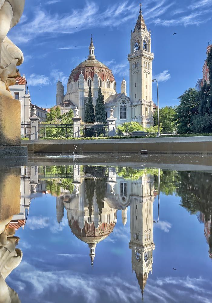 La iglesia de San Manuel y San Benito reflejada en las Cuatro Gracias