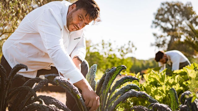 El chef Xanty Elías recoge uno de los productos que luego utilizará en su cocina en el huerto de la Finca Alfoliz