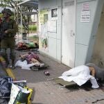 Israeli soldiers walk by a civilians killed by Palestinian militants in Sderot, Israel, on Saturday, Oct. 7, 2023. Palestinian militants in the Gaza Strip infiltrated Saturday into southern Israel and fired thousands of rockets into the country while Israel began striking targets in Gaza in response. 