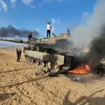 Palestinos celebran junto a un tanque israelí destruido en la valla de la Franja de Gaza, al este de Khan Yunis