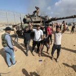 Palestinians take control of an Israeli tank after crossing the border fence with Israel from Khan Yunis. Palestinian militants in Gaza fired dozens of rockets at Israeli targets early on Saturday, the Israeli army said. 