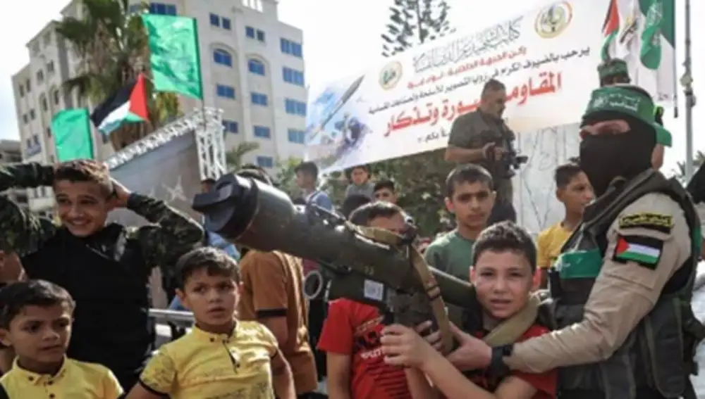 Un niño, con un lanzagranadas que le sujeta un miembro de Hamas