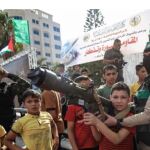 Un niño, con un lanzagranadas que le sujeta un miembro de Hamas