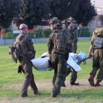 Soldados israelíes y personal médico llevan a toda prisa una camilla con una víctima a un helicóptero de las fuerzas israelíes