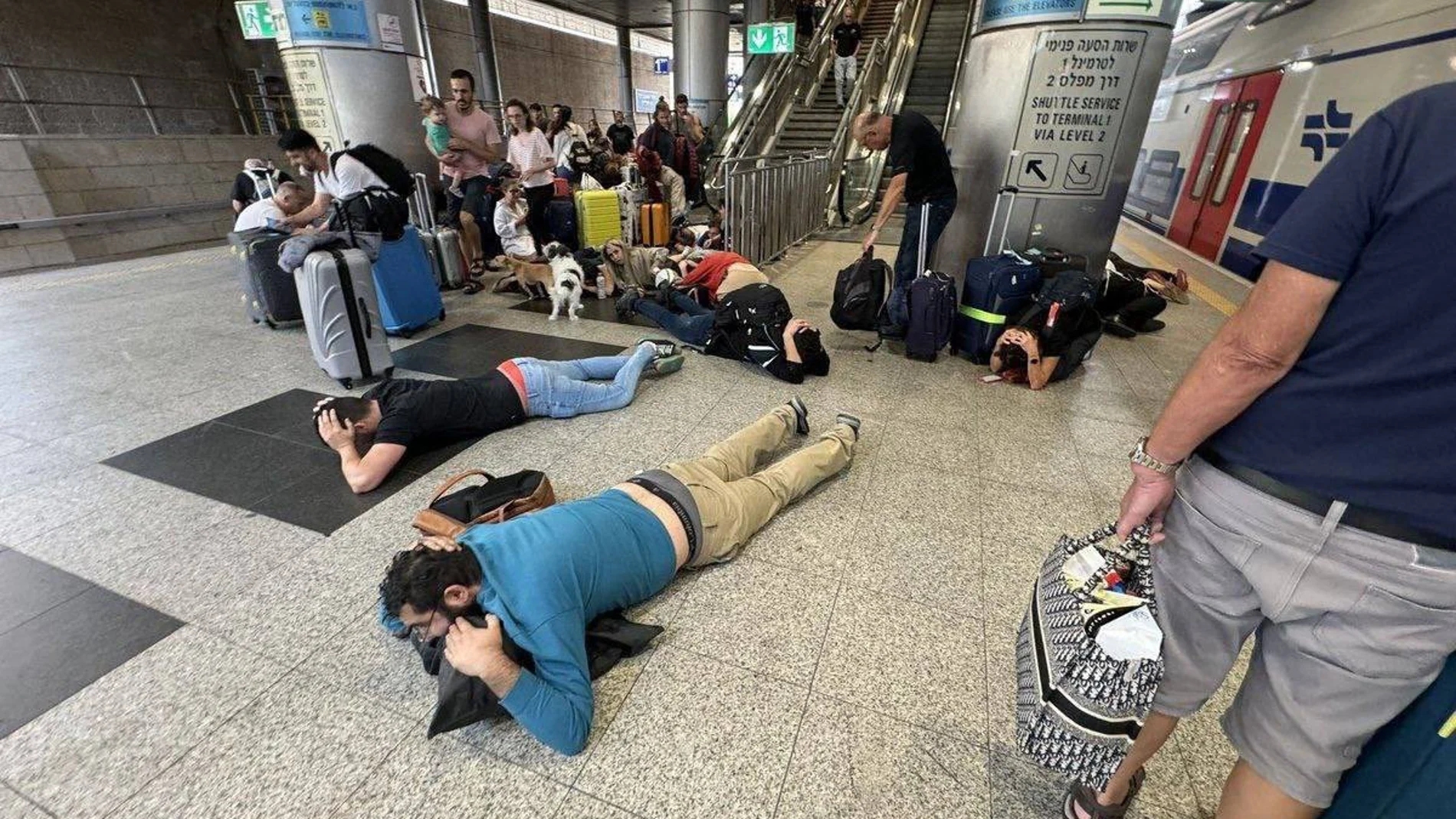 Pasajeros se refugian tras sonar la alarma antiaérea en el entorno del aeropuerto internacional israelí de Ben Gurion (Tel Aviv) 