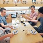 Turistas occidentales probando platos de sushi en un restaurante de Tokio
