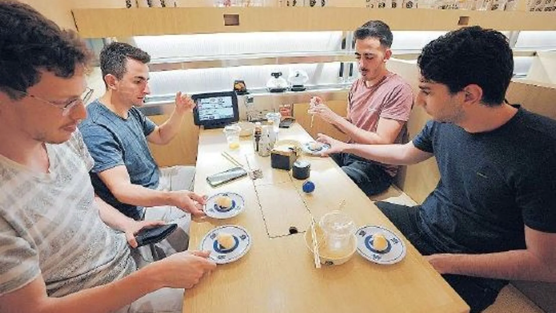 Turistas occidentales probando platos de sushi en un restaurante de Tokio