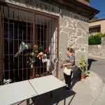 Una vecina deposita flores a las puertas del bar 'La Boyería', que regentaba la víctima, este martes en la localidad toledana de Pelahustán