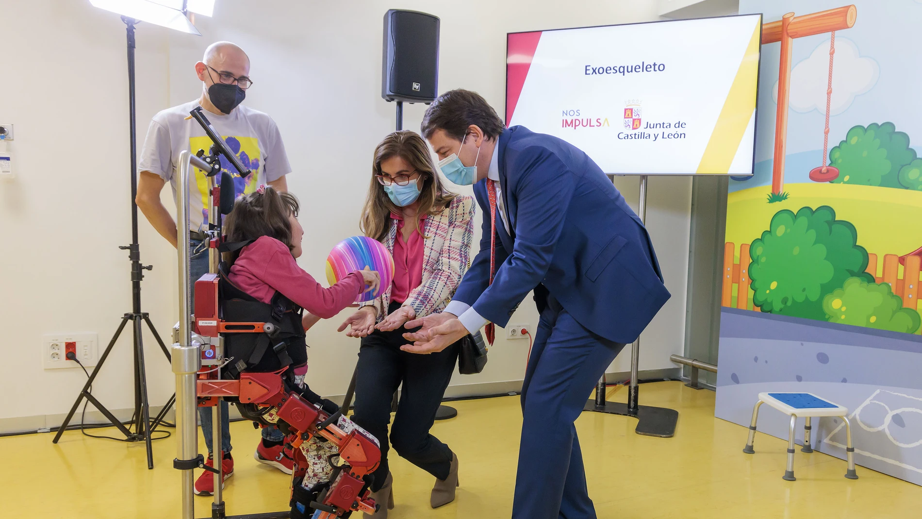 El presidente de la Junta, Alfonso Fernández Mañueco, junto a Lola, la niña que ha probado el exoesqueleto y sus padres Andrés Gutiérrez y Paula Aller