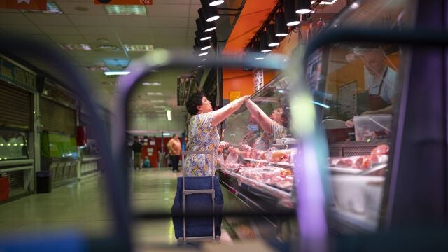 Mujer pagando en una carnicería de un mercado 